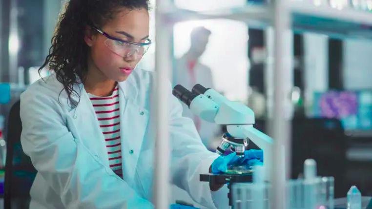 Imagem de uma profissional bioqímica olhando o resultado do exame no microscópio